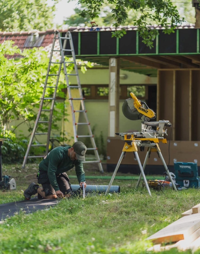 BOSK-medewerker aan het werk op een houtskelet totaalproject met cirkelzaag op de voorgrond