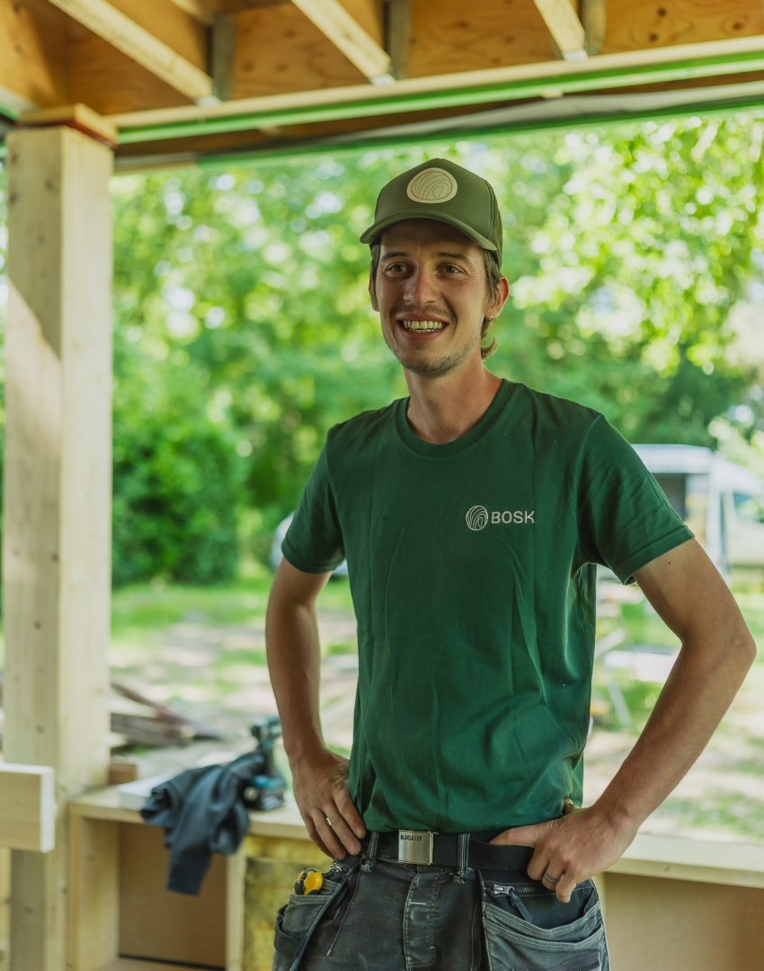 Andreas van BOSK Houtbouw in een houtskeletconstructie bezig met isolatiemateriaal plaatsen