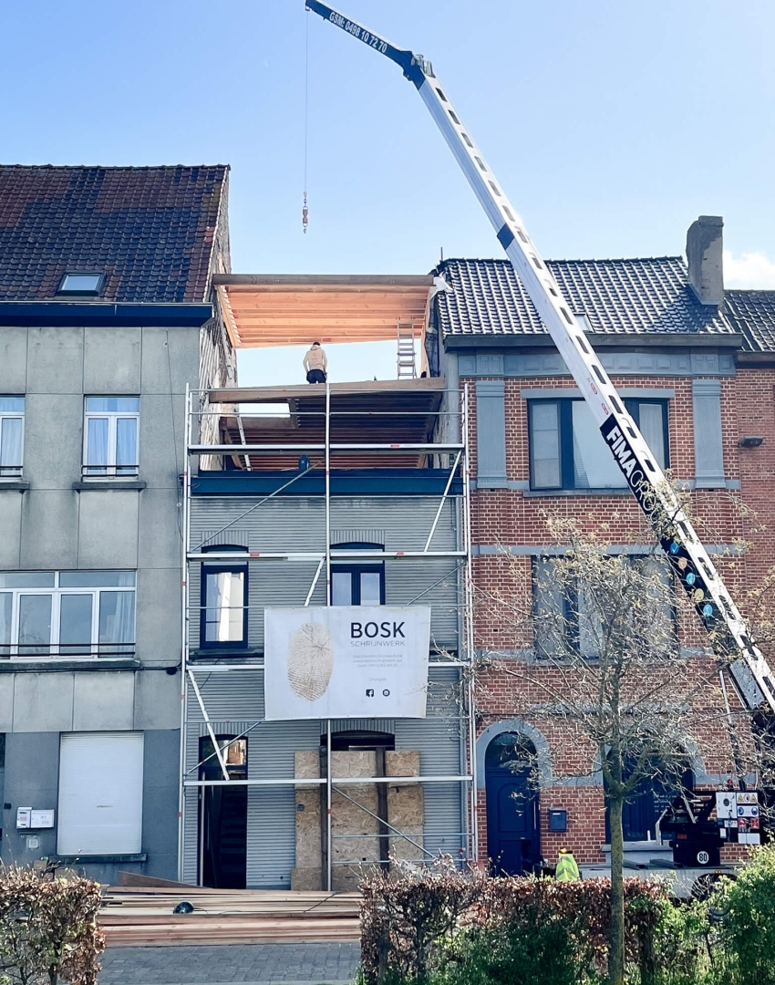 Optopping in houtskeletbouw met kraan, straatzicht tussen bestaande gevels Muide Gent